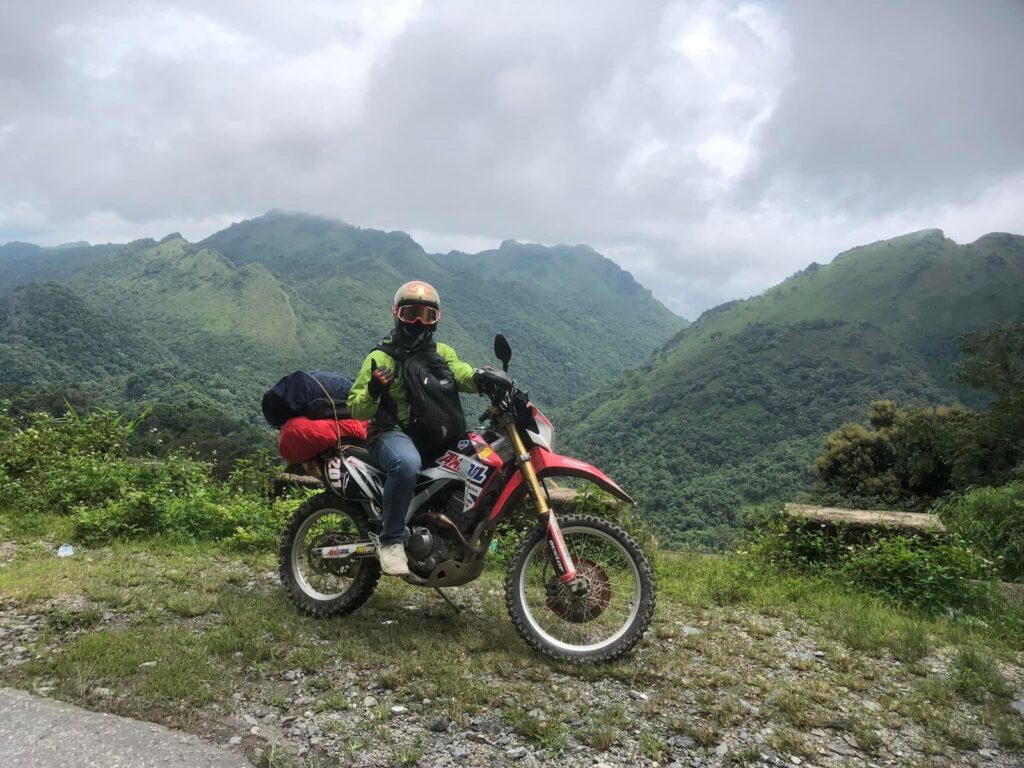 Rider on a motorcycle enjoying scenic mountain views in Laos